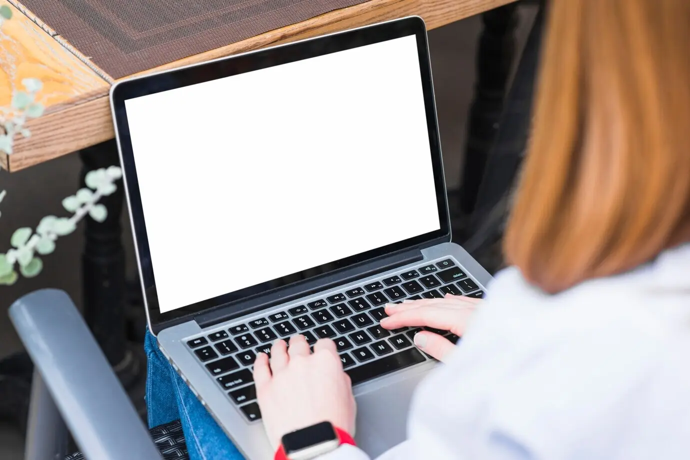 A close-up of a woman's hand using a laptop.